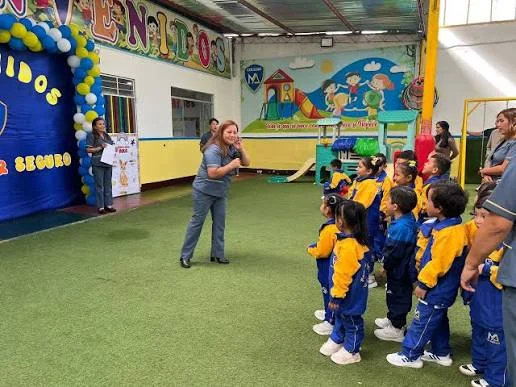Una mujer dirige una actividad con un grupo de escolares en un patio.